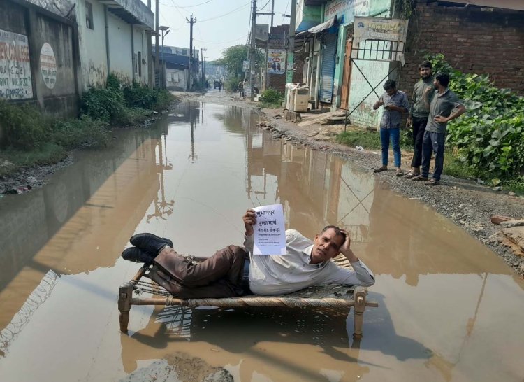 सड़क बनवाने के लिए कीचड़ में खाट डालकर लेटा पूर्व फौजी